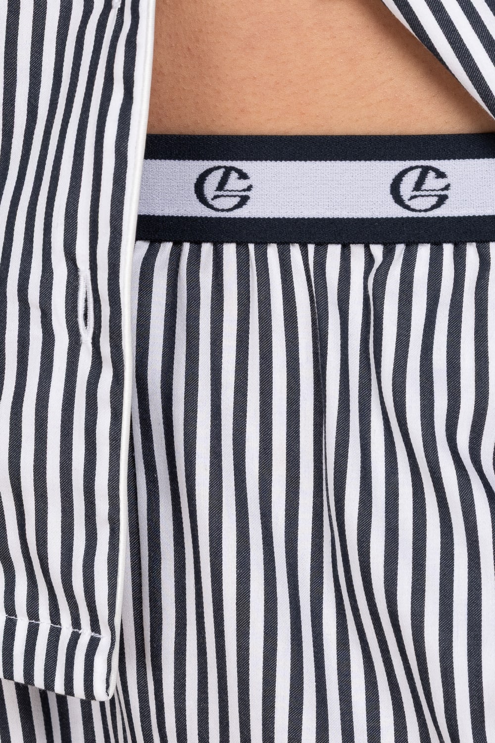 Close-up of navy and white striped pyjama pants with a brand logo on the waistband.