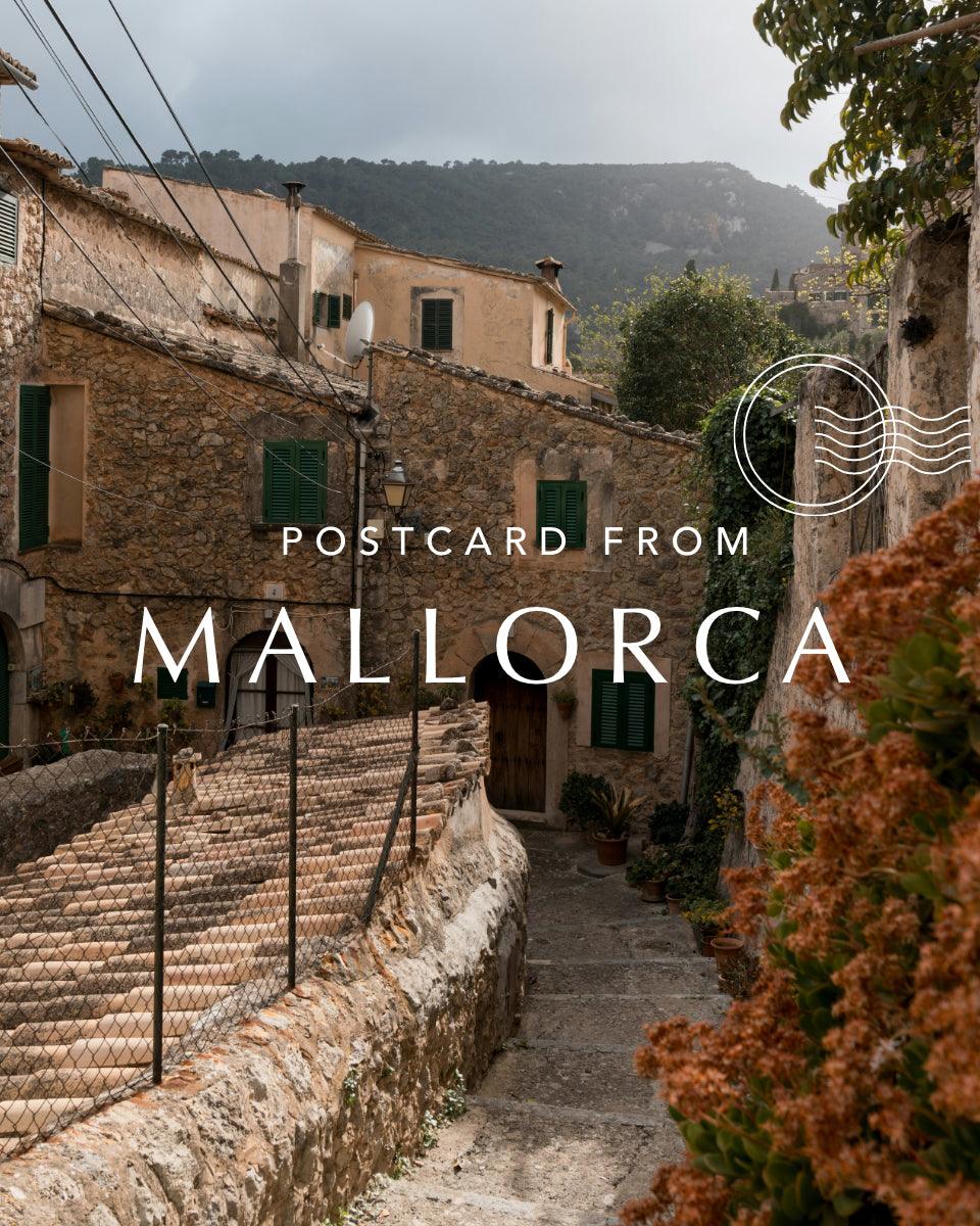 Charming Mallorca stone village alleyway with rustic houses, green shutters, and mountain view