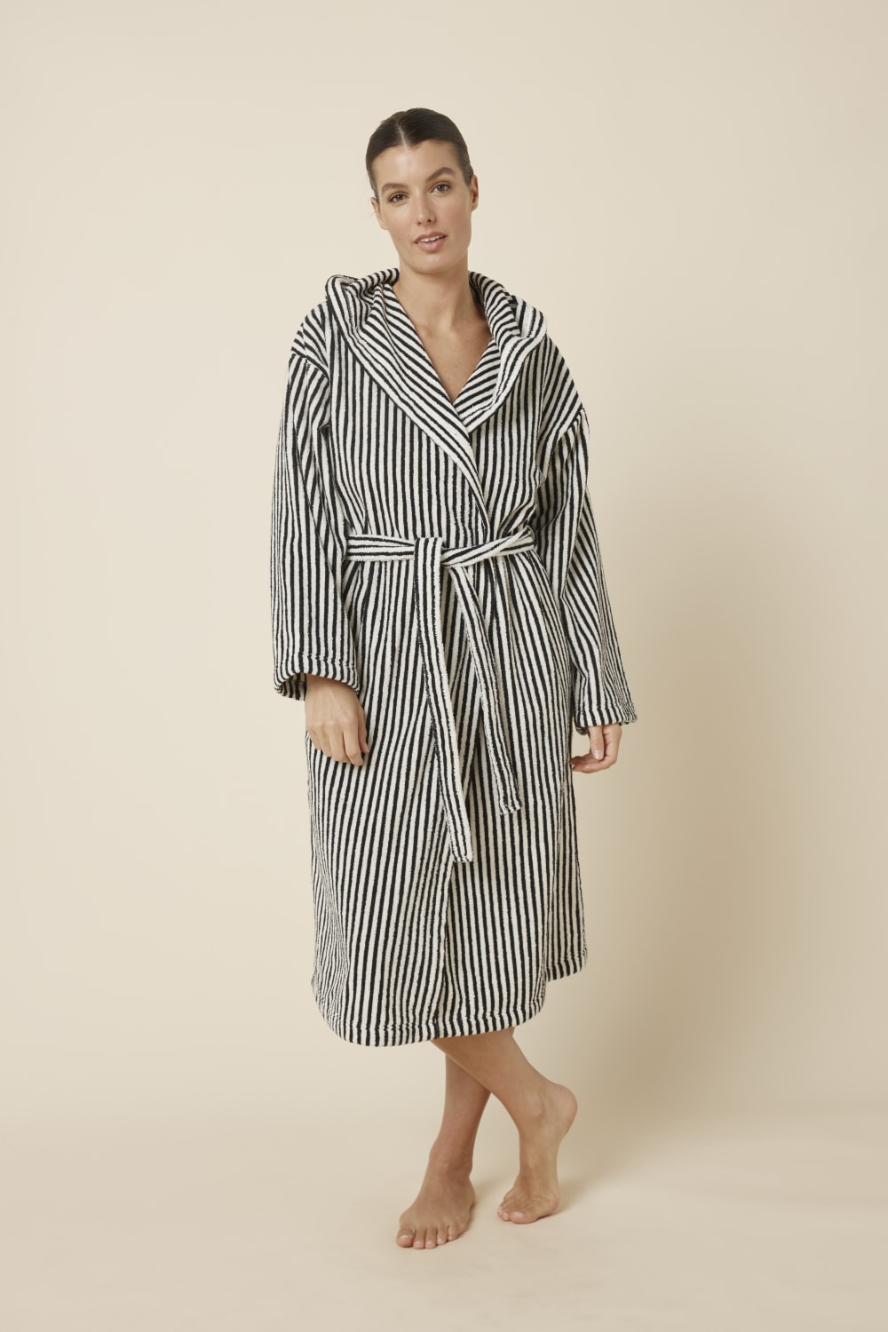 Woman wearing a striped adriana terry towel robe in black colour front on view standing with legs crossed