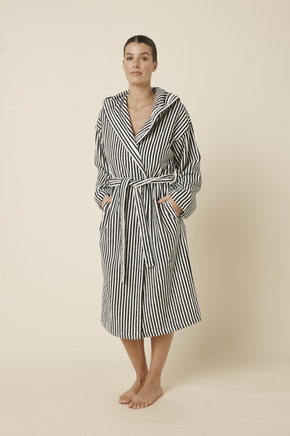 Woman wearing a striped adriana terry towel robe in black colour side on view with hands in pockets
