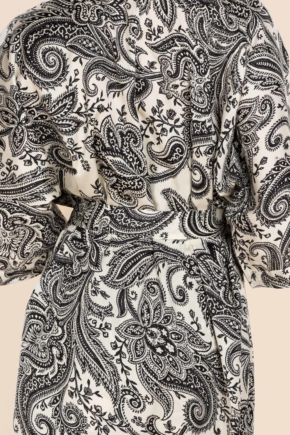 Close-up of a black paisley pattern on a beige background