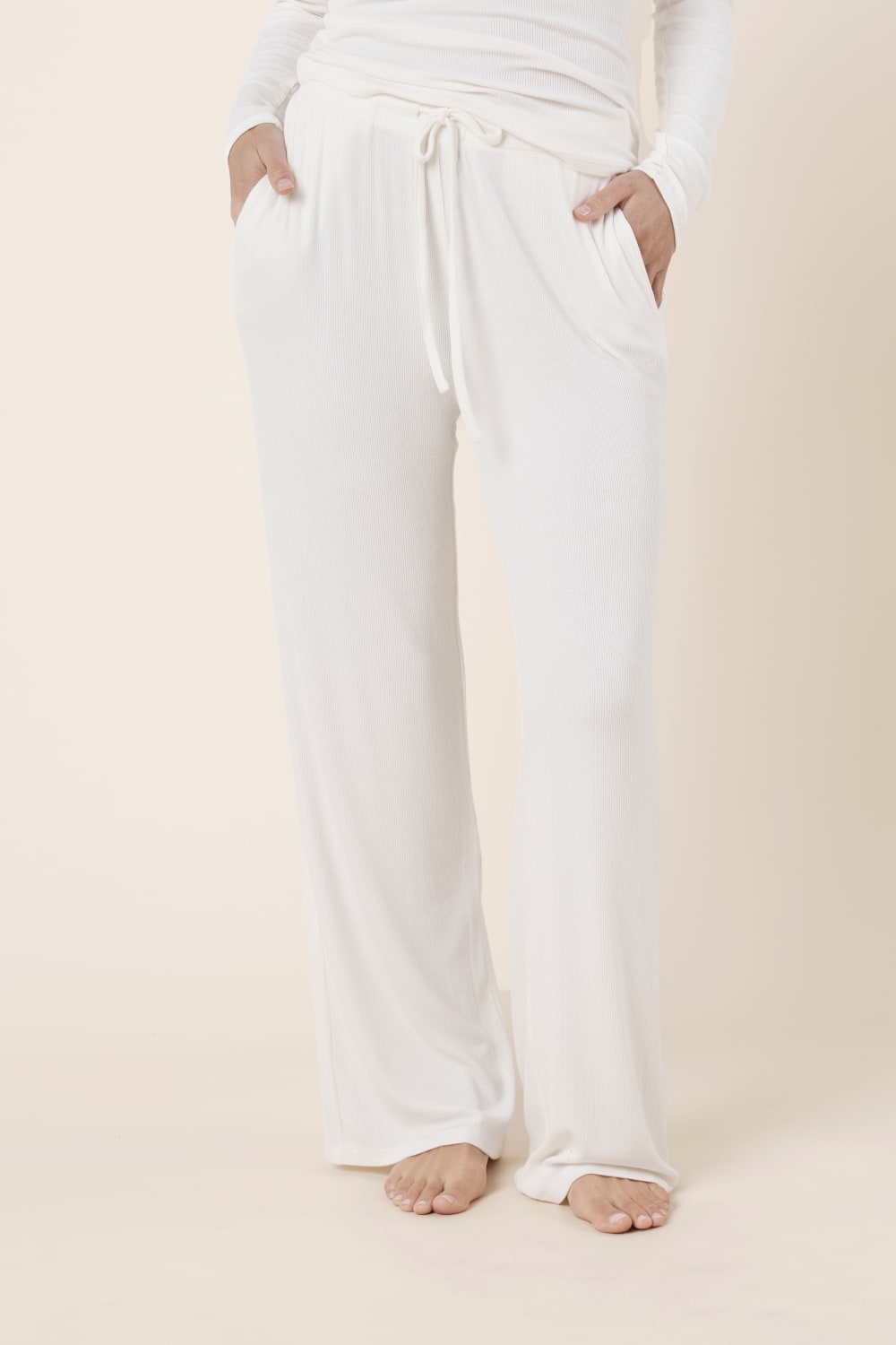 Woman wearing Athens Ribbed Long Pants Ivory, full length view of lightweight ribbed lounge pants with wide leg silhouette
