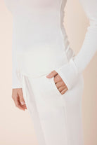 Woman wearing Athens Ribbed Long Pants Ivory, close up of ribbed fabric pocket with Gingerlilly logo detail