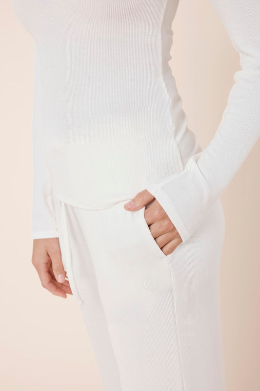 Woman wearing Athens Ribbed Long Pants Ivory, close up of ribbed fabric pocket with Gingerlilly logo detail