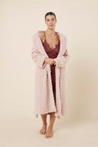 Woman wearing Azalia Silky Satin Short Chemise Burgundy styled with a light robe, showing the satin slip dress with lace trim and delicate straps.