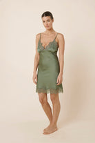 Woman wearing Azalia Silky Satin Short Chemise Olive walking slightly forward, showing the light silky satin fabric and lace trimmed hem moving naturally.