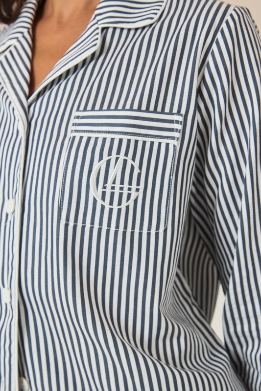 Close-up of the collar and embroidered logo pocket on a navy and white striped pajama shirt.