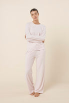 Woman wearing a ellie lightweight velour cable knit set pink long-sleeve top and pants on a beige background front on view with hands crossed