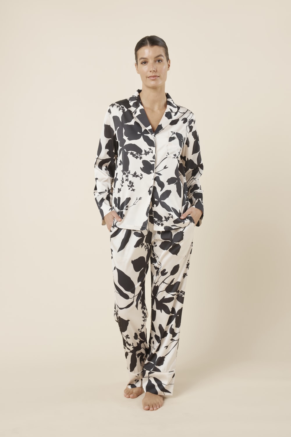 Woman wearing a black and white floral Ivy Silky Satin pyjama PJ set front on view with hands in pockets