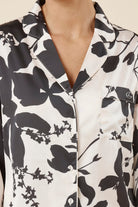 Close-up of the Ivy Silky Satin PJ set top featuring the black and white floral pattern and pocket with embroidery