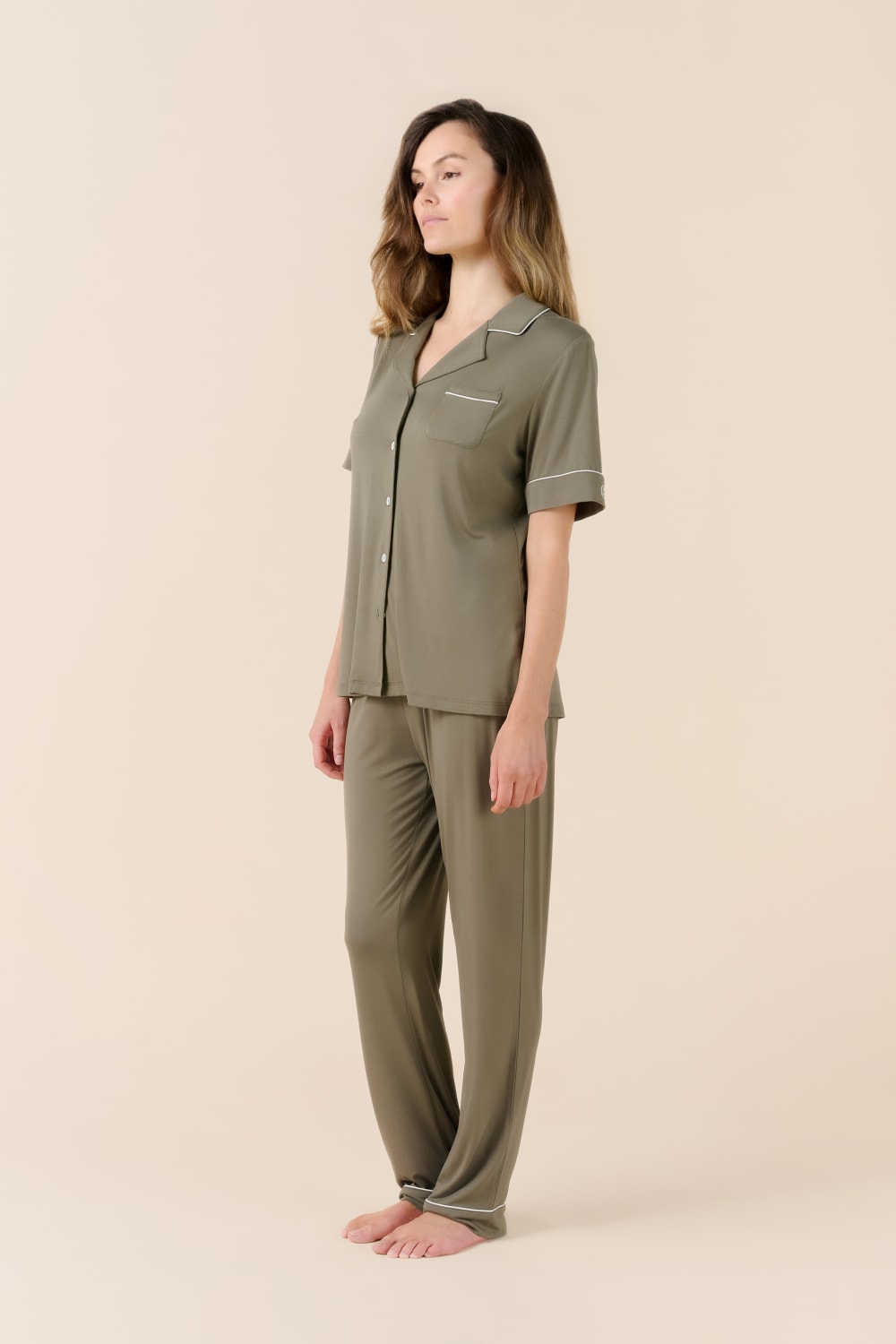 Woman wearing a green pajama set on a beige background