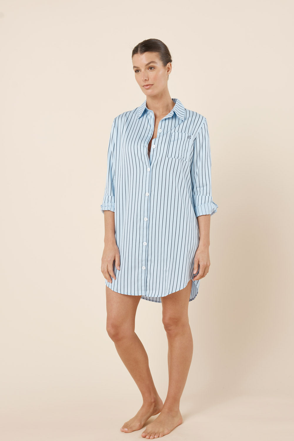 Woman wearing a light blue and white striped shirt dress on a beige background