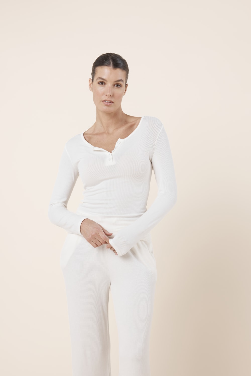 Woman wearing Lille Ribbed Long Sleeve Henley Top Ivory Ecru styled with matching ribbed lounge pants