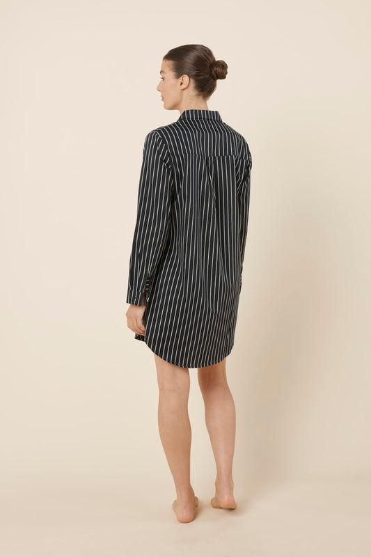 Woman wearing a black and white striped Lolita Stripe Night Shirt dress against a beige background back view