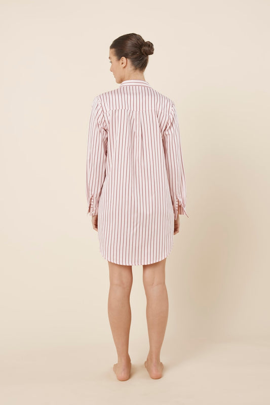 Woman wearing a pink striped Lolita Stripe Night Shirt dress against a beige background back view with arms beside her