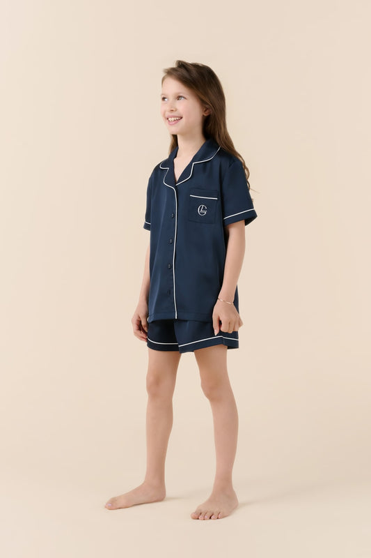 Girl wearing navy Gingerlilly Sleepwear short pyjama set with white piping on beige background