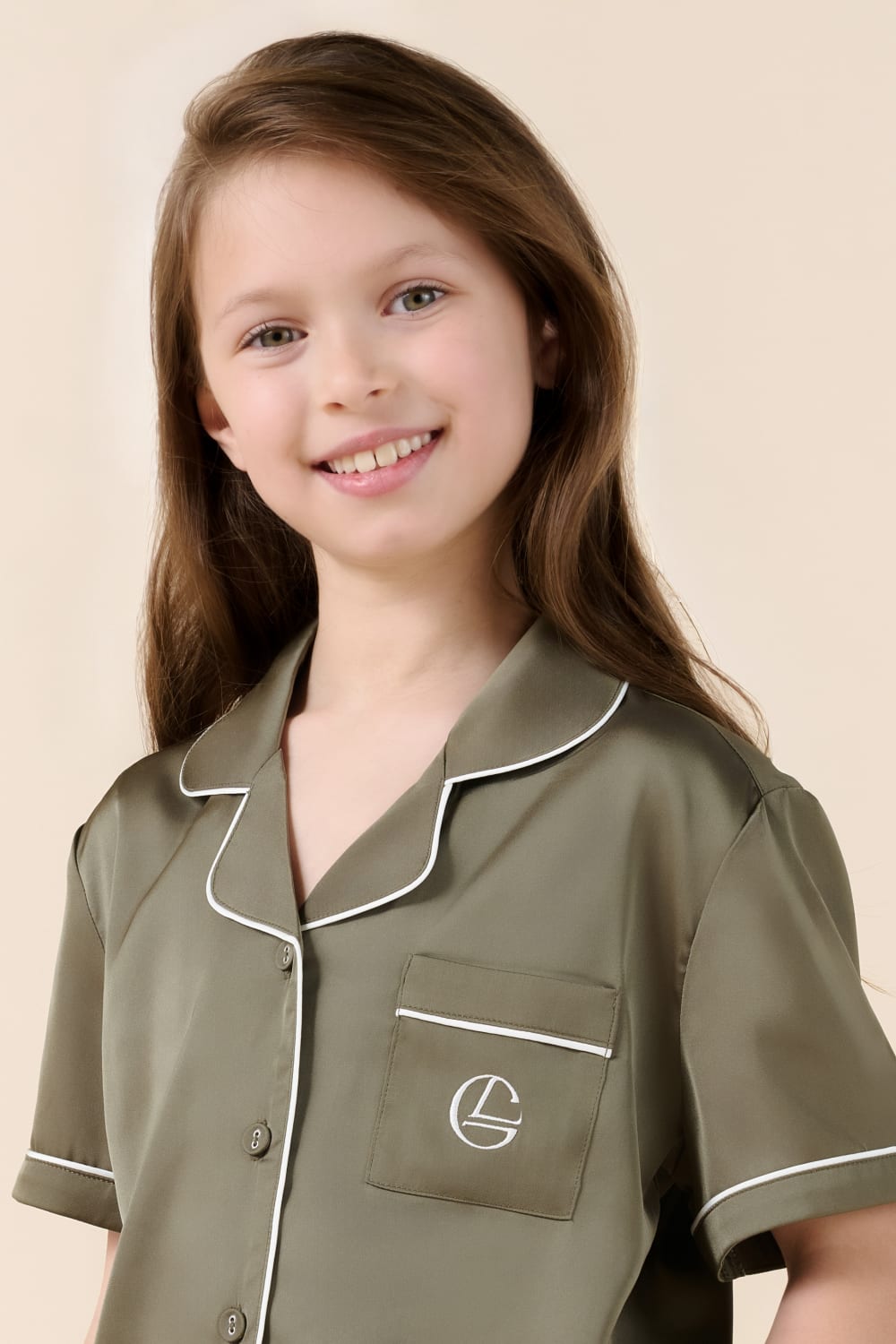 Smiling girl in olive green Gingerlilly Sleepwear pajamas with white piping details