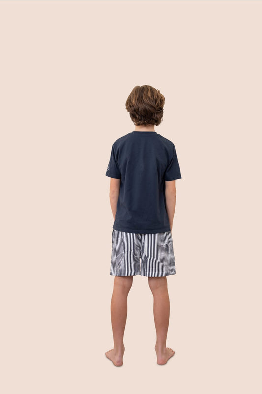 Child wearing a navy t-shirt and striped shorts on a beige background
