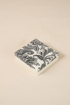 Black paisley patterned box on a beige background