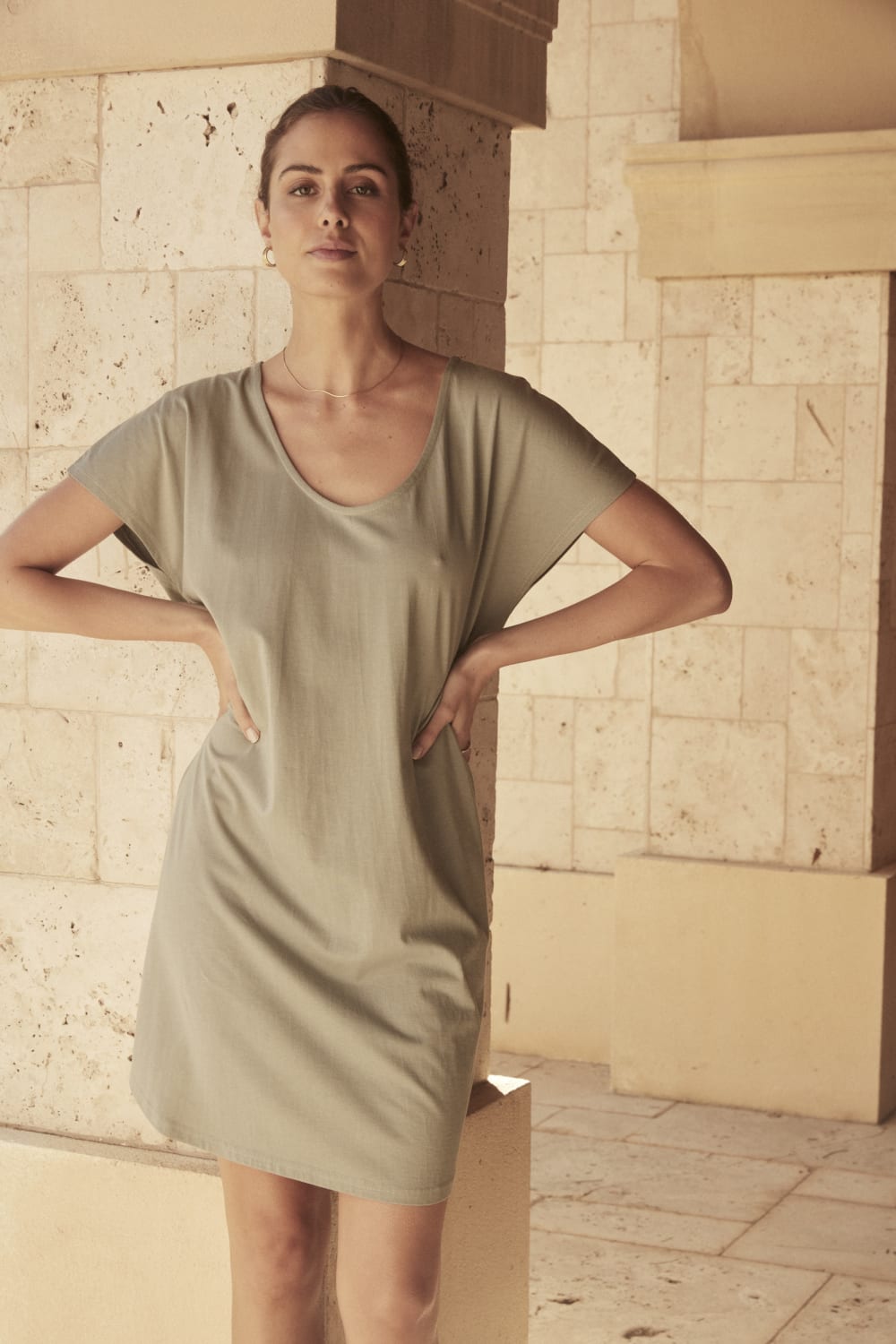 Woman in light sage short-sleeve Gingerlilly Sleepwear dress, natural stone background