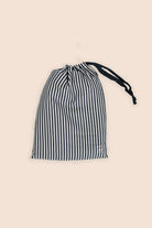 Black and white striped drawstring bag on a beige background