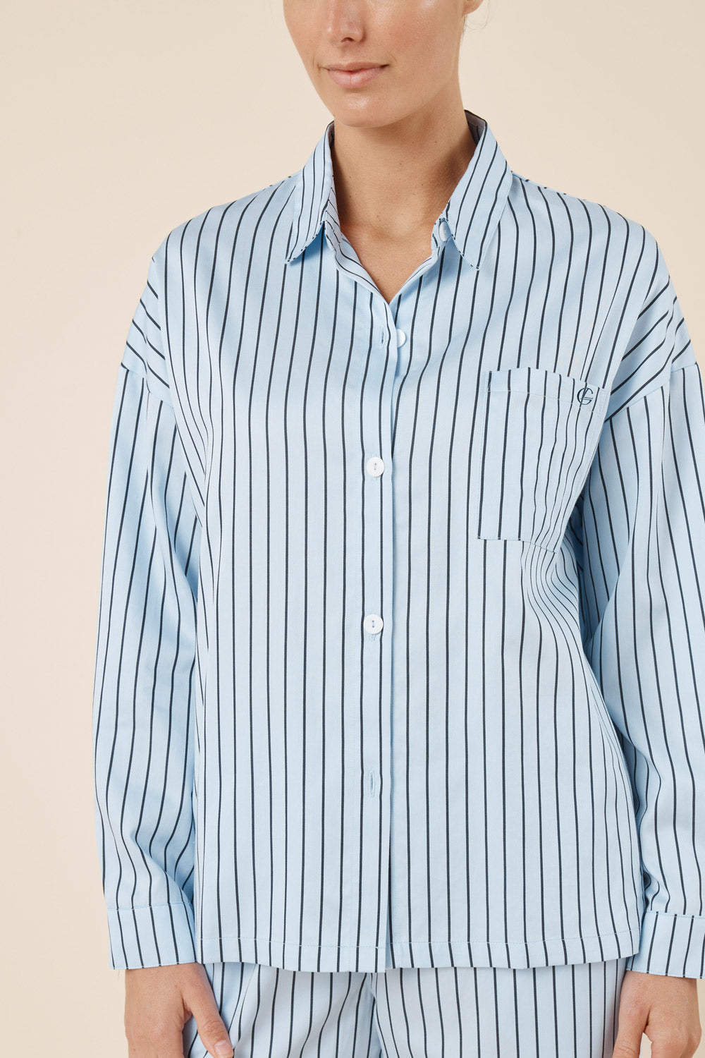 Person wearing a blue and white striped pajama set against a beige background