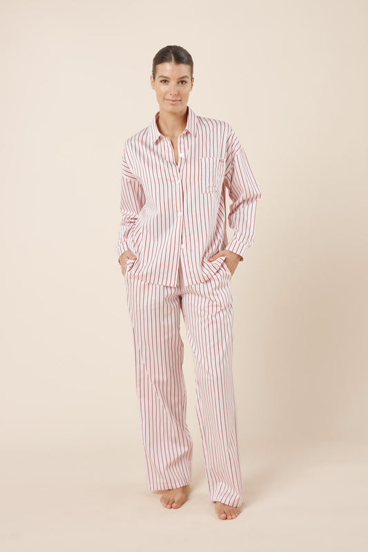 Woman wearing a red and white striped pajama set on a beige background