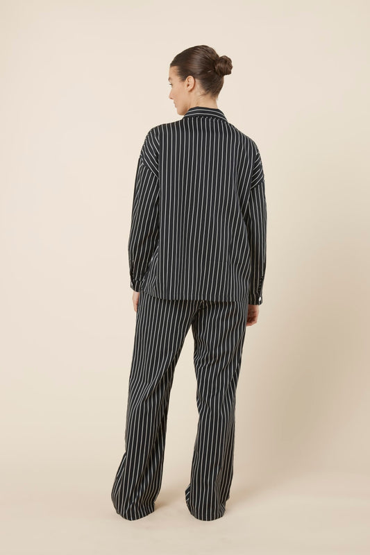 Woman wearing a black and white striped willow cotton stripe pyjama PJ set in set on a beige background and back view