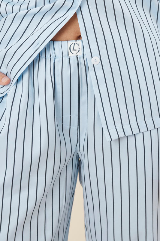 Woman wearing a blue striped willow cotton stripe pyjama PJ set with close up of waistline showing gingerlilly logo and white buttons