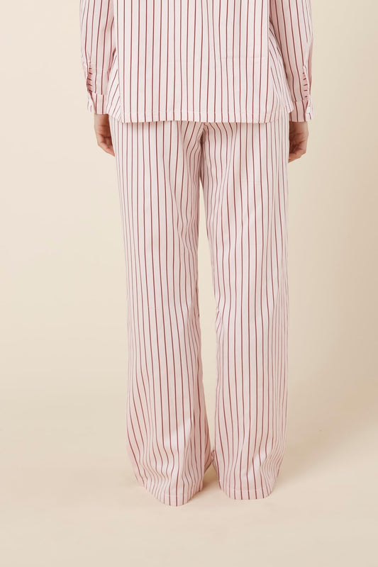 Person wearing willow cotton striped pant in pink and white stripe back view on a beige background