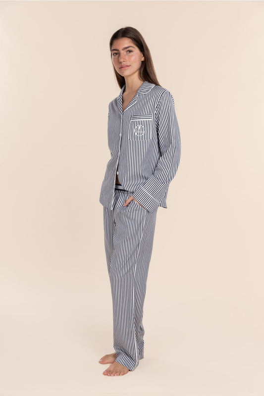 Woman wearing a blue and white striped pajama set on a beige background