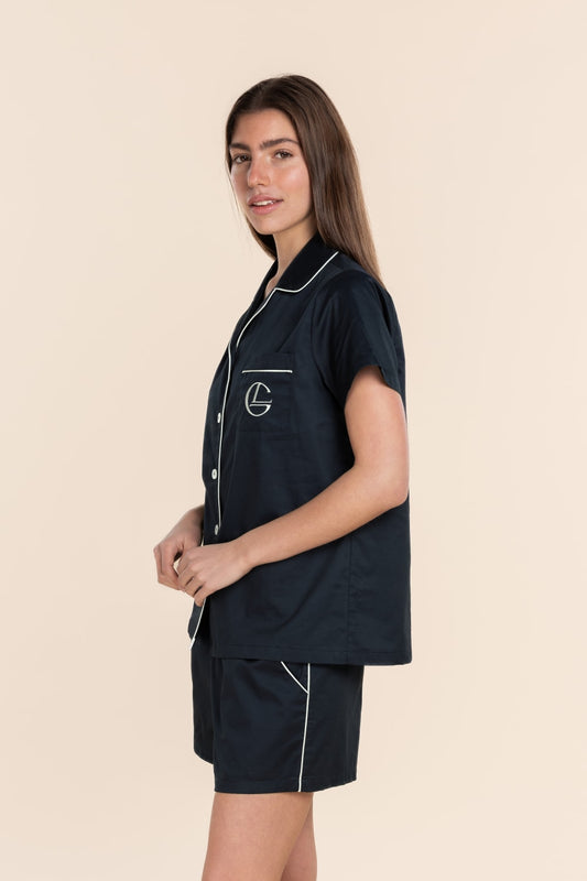 Woman wearing a navy outfit with white piping on a beige background