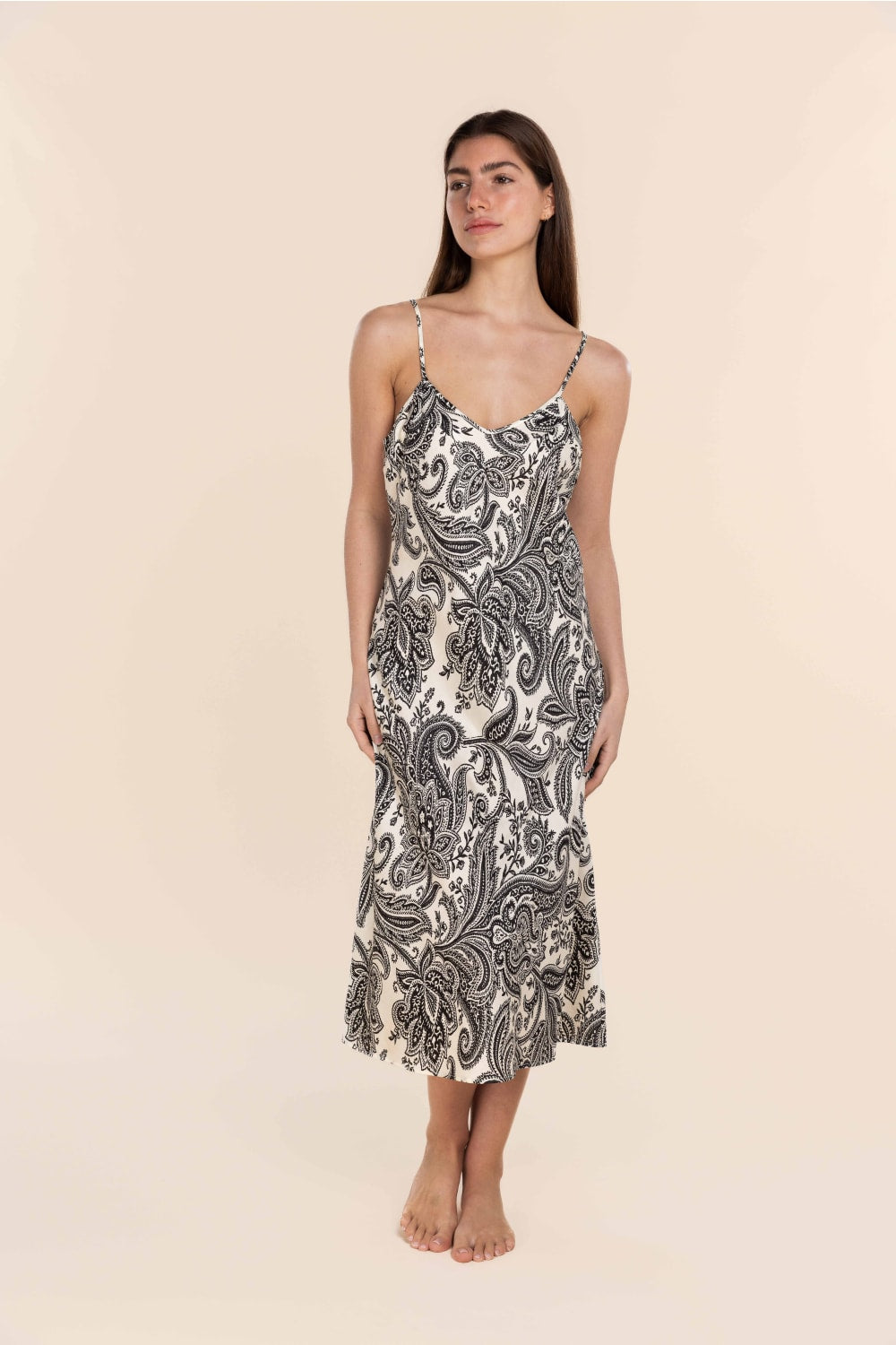 Woman wearing a patterned slip dress against a beige background