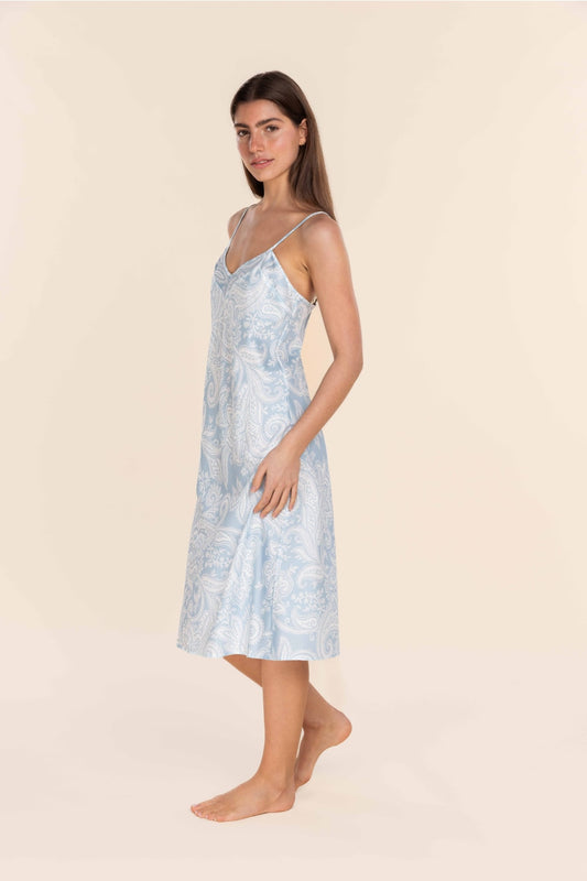 Woman wearing a light blue patterned dress against a beige background
