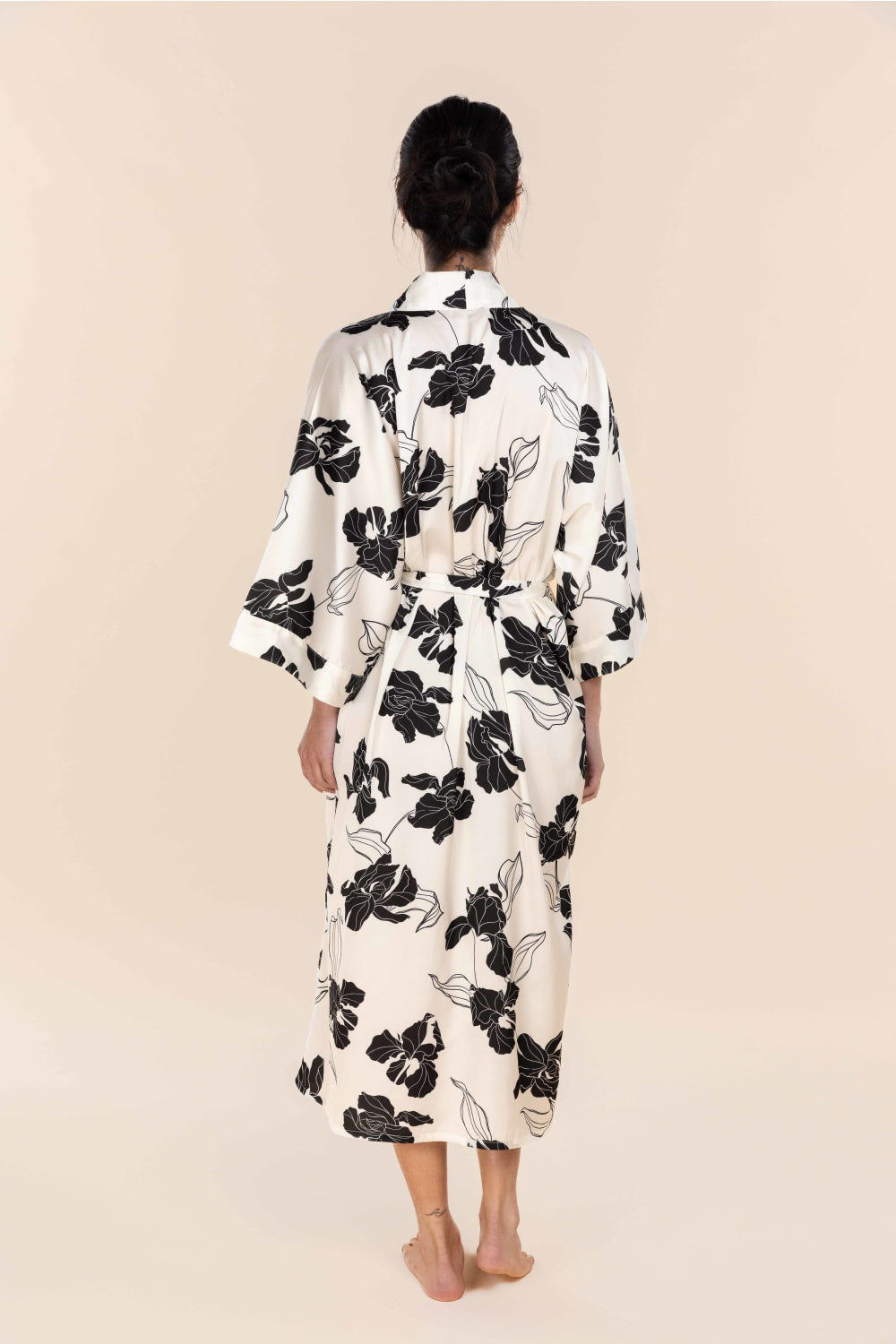 Person wearing a black floral patterned dress on a beige background