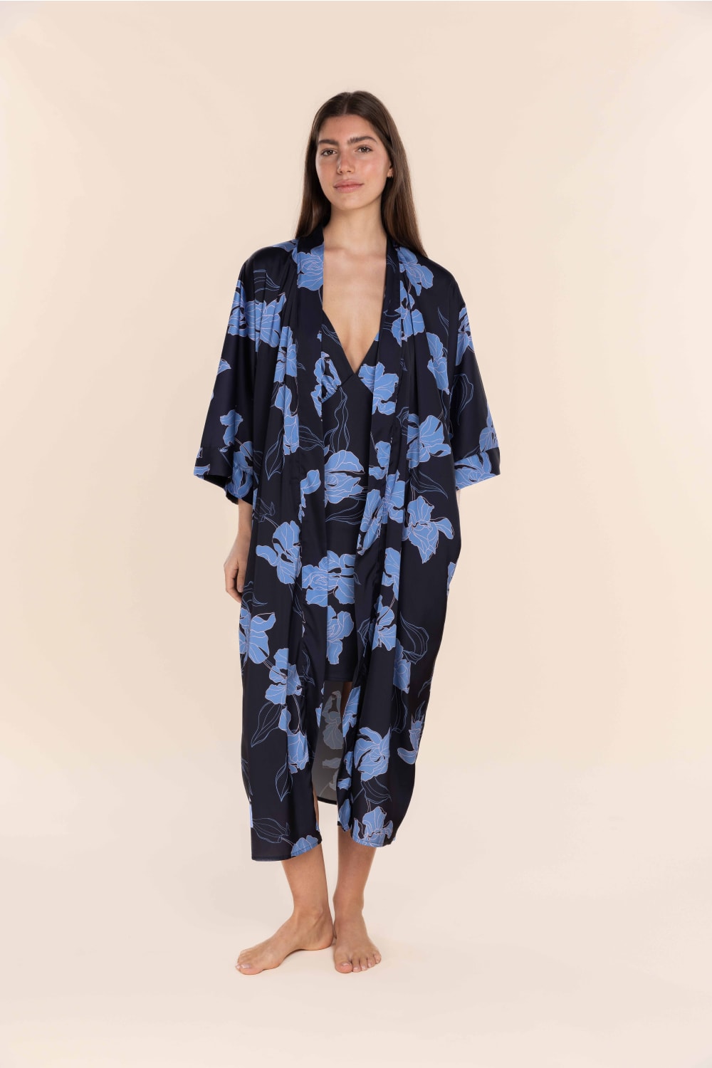 Woman wearing a black floral kimono against a beige background