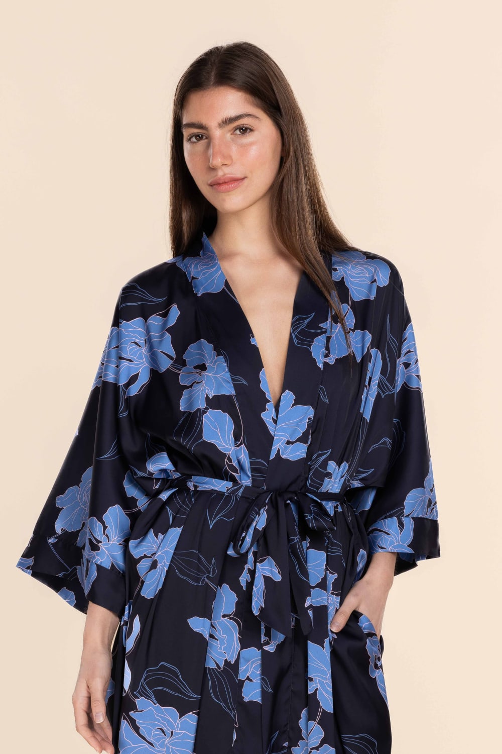 Woman wearing a black floral kimono-style dress on a beige background
