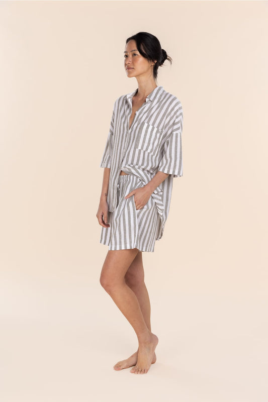 Woman wearing a striped shirt and shorts set on a beige background