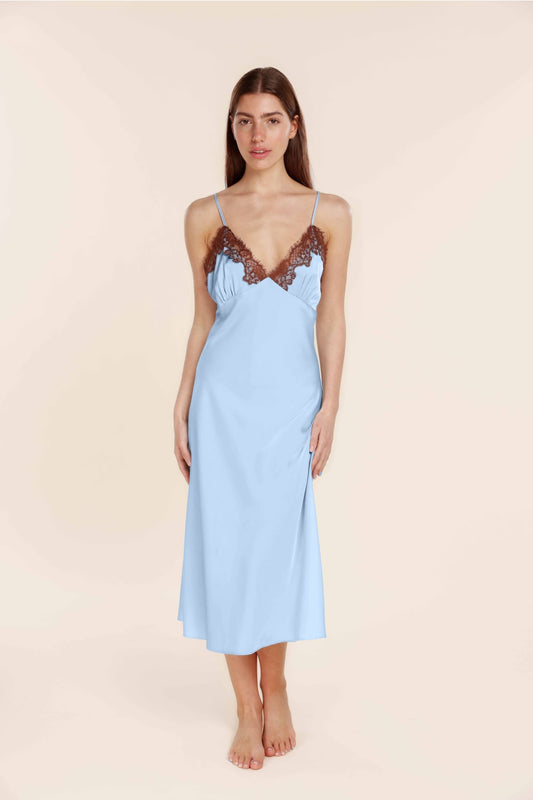 Woman wearing a light blue slip dress with lace details on a beige background