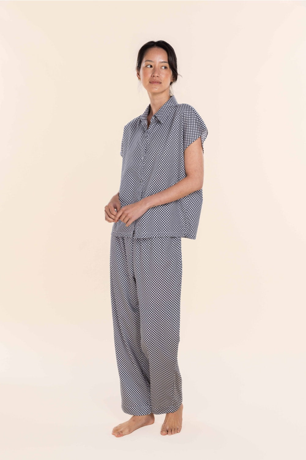 Woman wearing a blue checkered pajama set on a beige background
