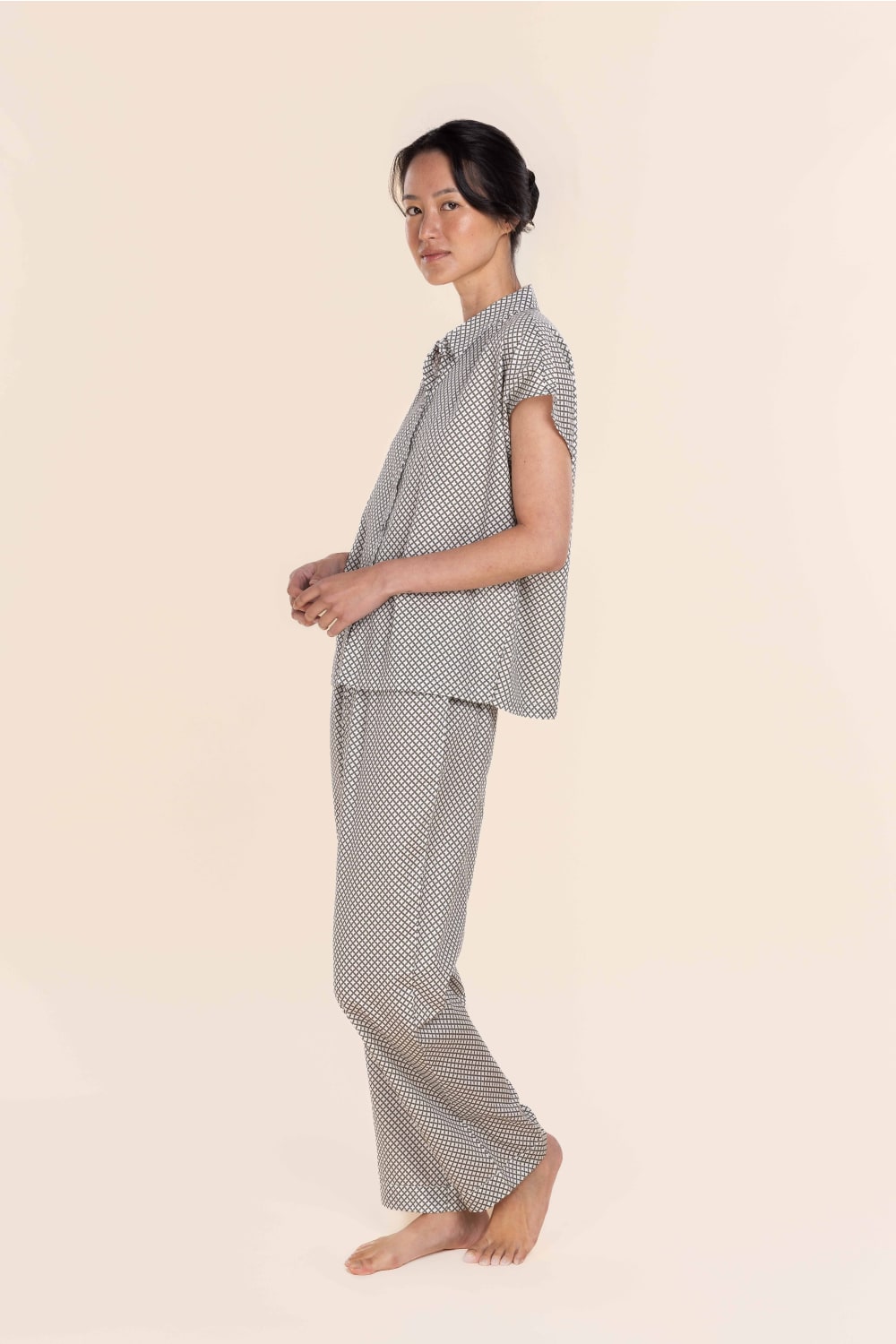 Woman wearing a checkered pajama set on a beige background