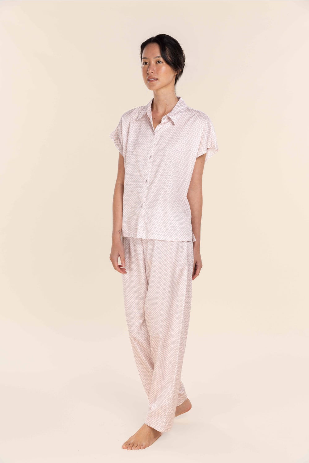Person wearing a light pink pajama set on a beige background