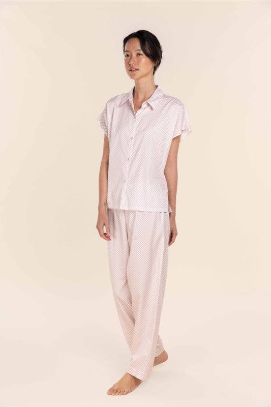 Person wearing a light pink pajama set on a beige background