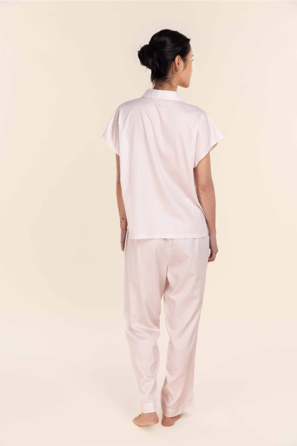 Person wearing a white t-shirt and beige pants on a plain background