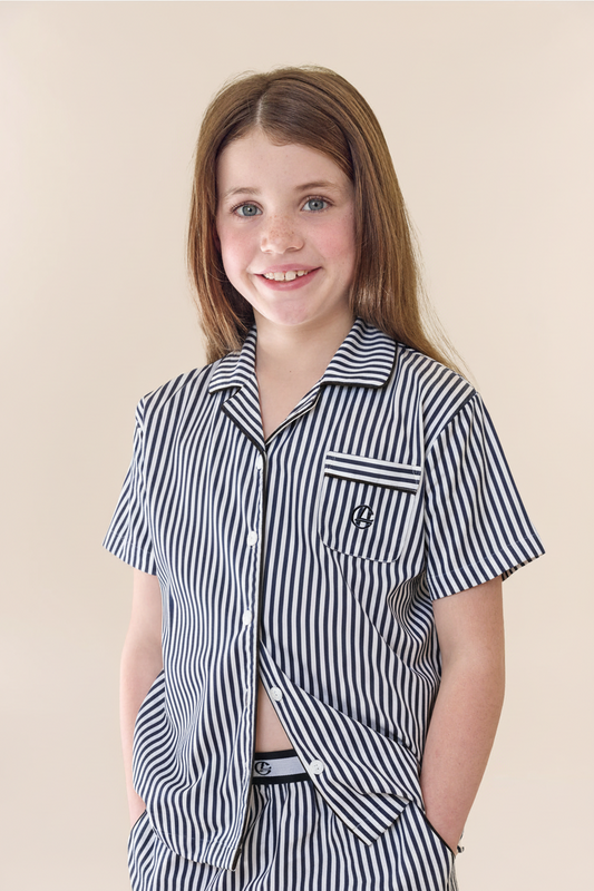Young girl wearing a black and white striped shirt with a beige background