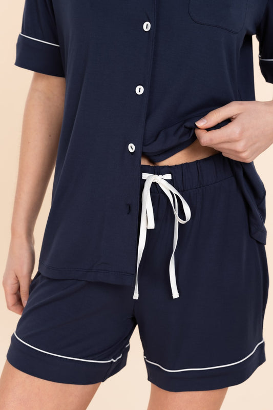 Navy pajama set with white trim on a beige background