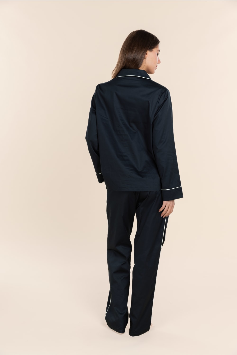 Person wearing a black outfit on a beige background