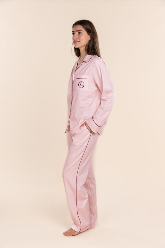 Woman wearing pink pajamas with a logo on a beige background
