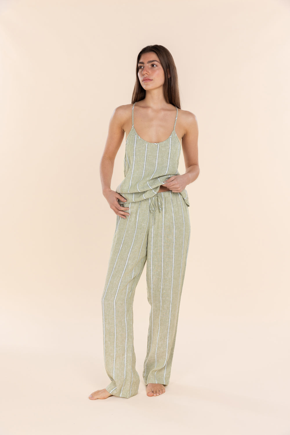 Woman wearing a green striped pajama set on a beige background